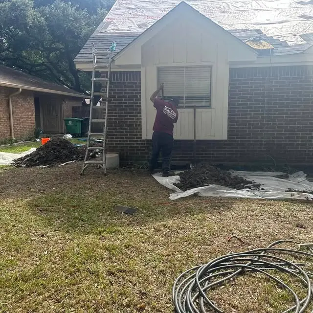oundation repair crew working on a residential home affected by soil movement in Spring, TX.