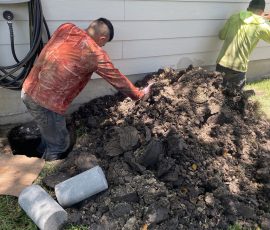 Two of our crew digging out along a Houston home's foundation with concrete piers ready to go in