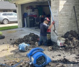 Working through a foundation repair beside a garage, with drying equipment running on the driveway