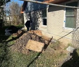 Foundation repair in progress with excavation along the exterior of a residential home. Access points are opened around the foundation so crews can complete stabilization work.