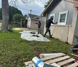 House leveling crew preparing access points along a residential foundation for pier installation. The work helps stabilize settled areas and restore proper support beneath the home.