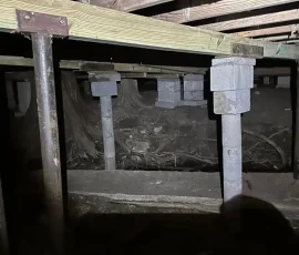 Pier and beam foundation crawl space showing wood framing and support piers beneath a home. Regular inspections help identify moisture, shifting supports, and other issues before they affect foundation stability.